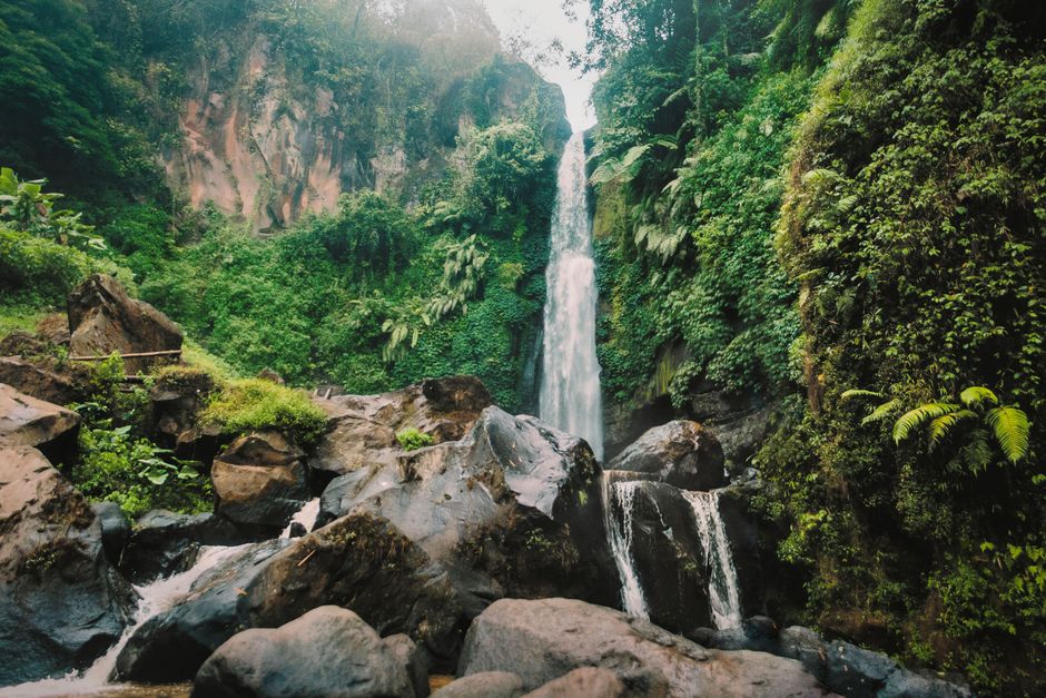 A breathtaking view of a waterfall cascading through rocky terrain surrounded by lush greenery.